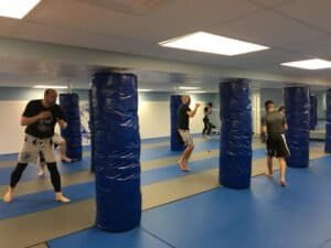 Boxing students practicing punches and footwork in a training gym.