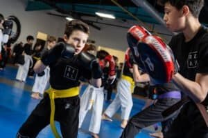 Young boy practicing boxing with instructor in martial arts class.