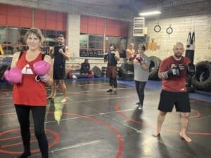 Group of people boxing in a gym with boxing gloves and equipment.