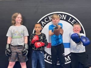 Young children practicing boxing with gloves at Quest Grappling Academy.