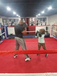 Adult and child boxing training in the gym ring at Hammer Fitness.