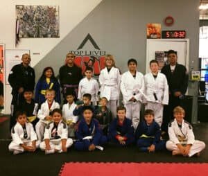 Group of children and instructors in judo uniforms at Top Level MMA gym.