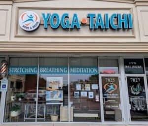 Yoga Tai Chi studio storefront with signs for stretching, breathing, meditation classes.