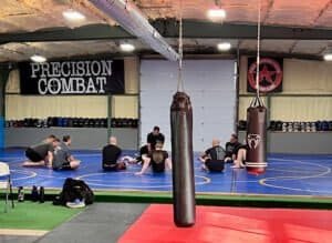 Boxing training session at Precision Combat Sports gym with coach and students.