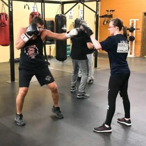 Boxer practicing punch techniques with trainer at MAX Martial Arts & Fitness gym.