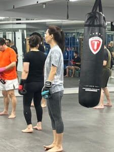 Women training with punching bag at KFF Kick Boxing Club gym.
