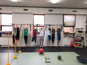 People exercising on pull-up bars in a fitness gym.