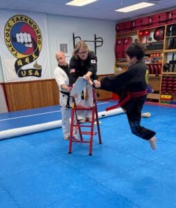 Young student practicing flying kick with instructor at Taecole Tae Kwon Do.