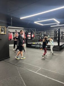Kids practicing boxing techniques in a modern gym with coach supervision.