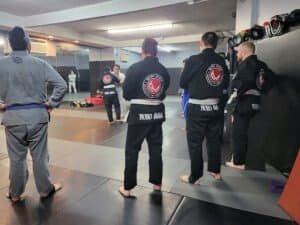 Martial arts students in gi practicing techniques at NoHo MMA gym.