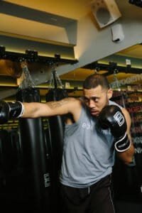 Male boxer practicing punches in gym with punching bags.