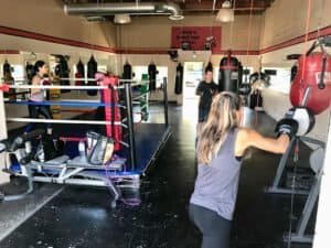 Women boxing training at Adams Bootcamp with punching bags and trainers.