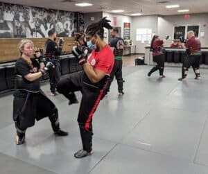 People practicing boxing techniques in a gym with trainers and students.