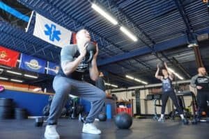 Man performing kettlebell squat in MMA gym with others training.