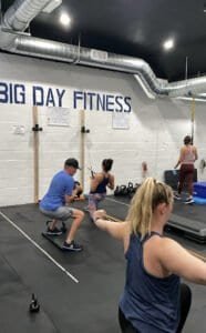 People exercising at Big Day Fitness Norwell gym with weights and mats.