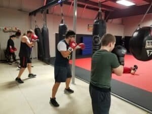 Group of fighters practicing boxing and striking techniques in a gym.