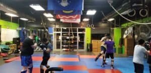 People practicing MMA and fitness exercises in a gym environment.