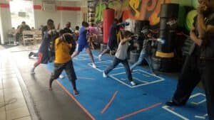 Children practicing boxing techniques in a training gym with punching bags.