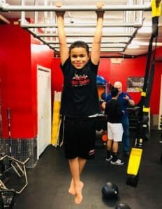 Young boy hanging from gym equipment at a boxing gym in Philadelphia.