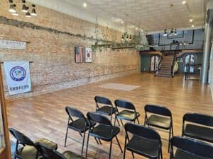 Indoor martial arts training space with chairs and brick wall.