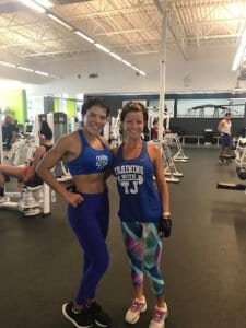Two women in workout gear smiling after training session at gym.