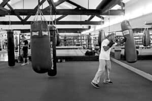Boxer practicing punches on heavy bag in old school boxing gym.