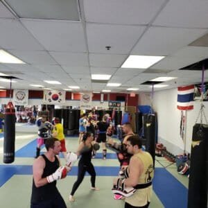 Boxers training with focus mitts and punching bags in gym.