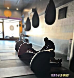 Boxers stretching and warming up in a boxing gym with punching bags.