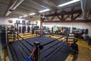 Empty boxing ring inside Rick Ramos Boxing Gym with training equipment.