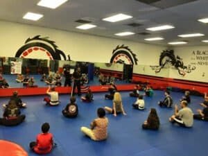 Kids and adults practicing martial arts in a dojo with dragon wall art.