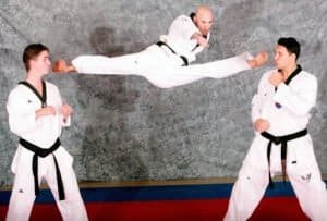 Martial arts students practicing high kick and sparring techniques.