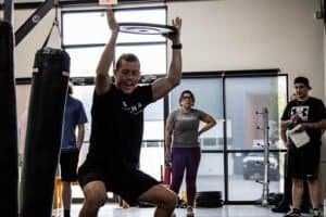 Man practicing kickboxing techniques in gym with trainers and students.