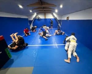 MMA students practicing grappling techniques in a blue training room.