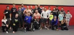 Group of mixed martial arts fighters and trainers at Checkered Past MMA Gym.