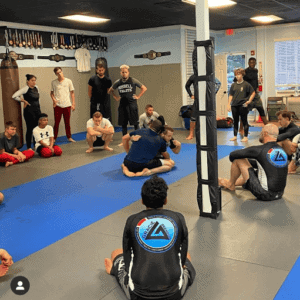Group of students practicing Brazilian Jiu-Jitsu techniques in a gym.
