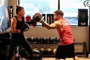 Female boxer practicing with trainer in boxing gym at TITLE Boxing Club South Tampa.