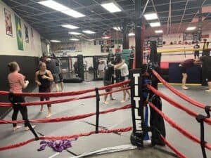 People training in a boxing gym with rings and punching bags.