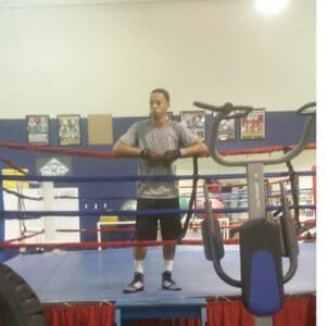 Young male boxer standing in boxing ring during training session.