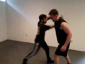 Two men practicing boxing techniques in a training room.