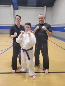 Young martial artist with instructors in a gymnasium.