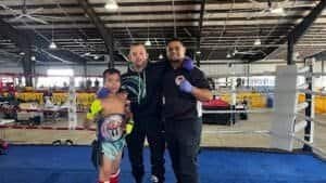 Young boxer with trainers in boxing gym at Coastal Muay Thai.