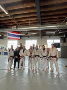 Group of martial artists in Jiu-Jitsu and Muay Thai gi uniforms.