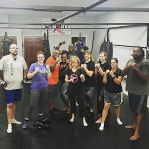 Group of diverse people in boxing gym with gloves and punching bags.
