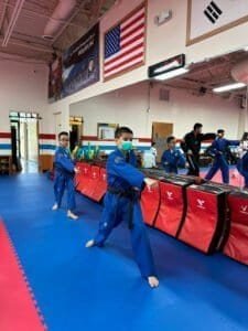 Children practicing martial arts in a gym with American flags and martial arts banners.