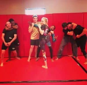Group of fighters practicing MMA techniques in a red training room.