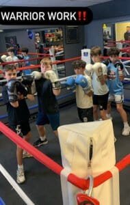 Young boys training with boxing gloves in a boxing gym.