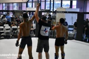 Referee raises winner's hand in MMA match at Ground Dwellers Texas Roots.