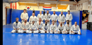 Judo practitioners in gi uniforms on blue mat at Kaizen Fitness Arts LLC.