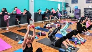 Women participating in a group fitness class doing wall exercises and stretches.