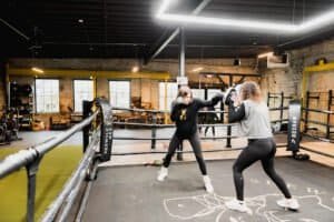 Women boxing training session at SheWolf MKE gym with coach.